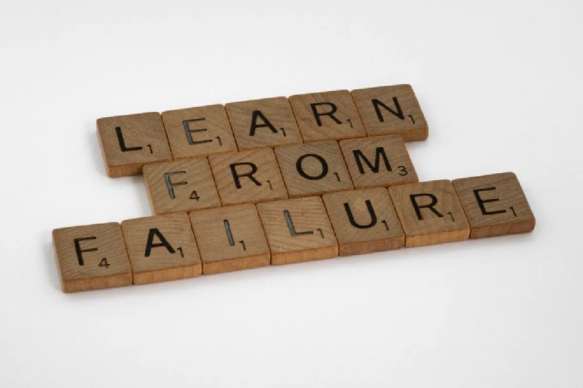 Wooden Scrabble tiles spelling 'Learn from Failure' on a white background, promoting resilience.