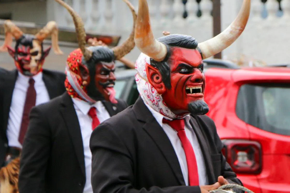 Men in devil costumes participate in a vibrant traditional street festival.
