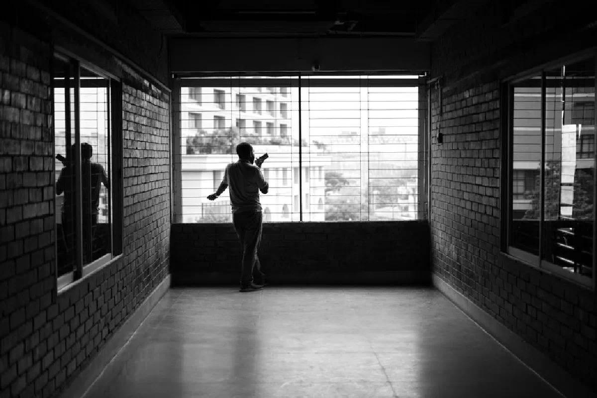 Silhouette of a person near window in a modern corridor with urban view, black and white photo.