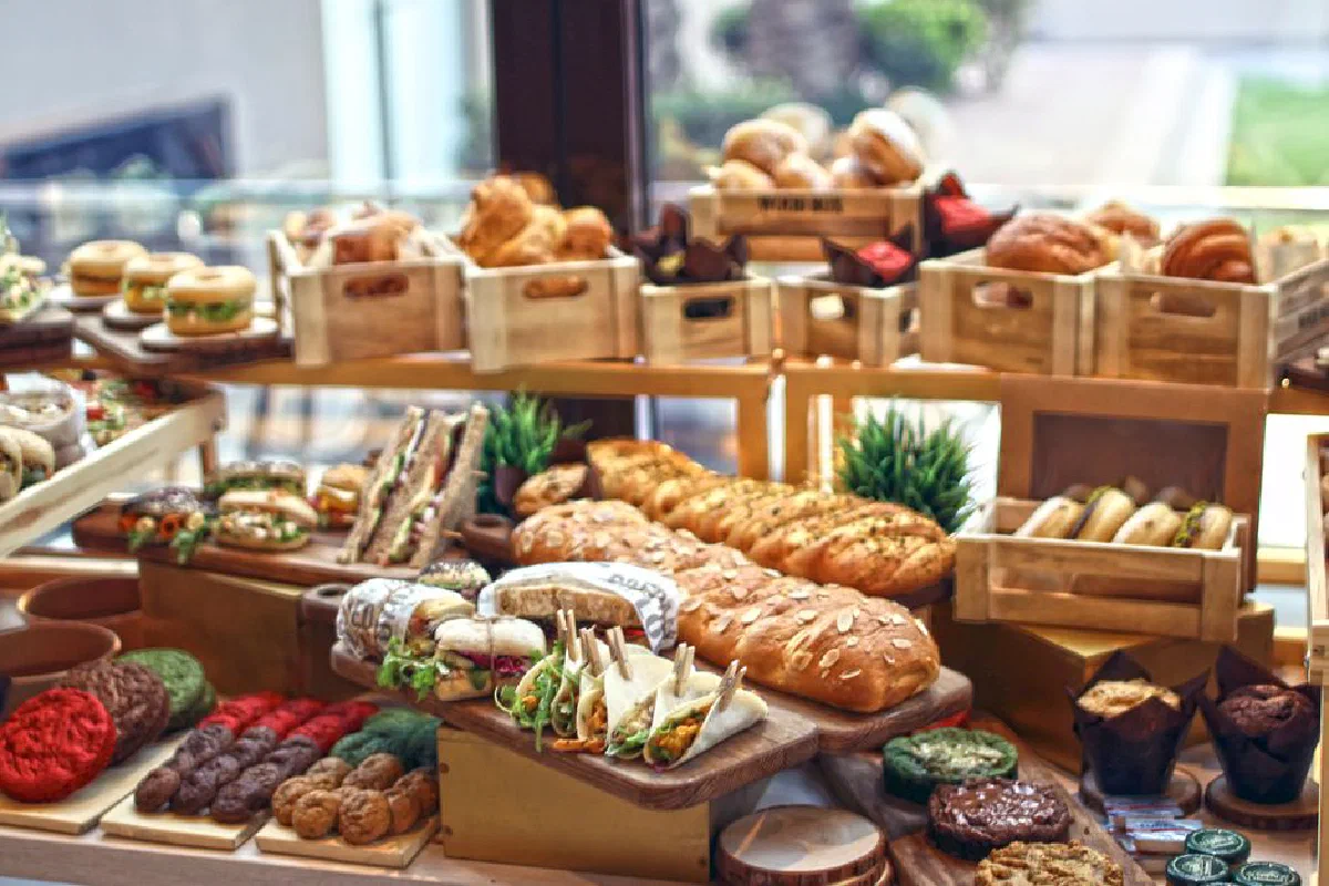 A vibrant display of assorted gourmet breads, sandwiches, and baked goods on wooden trays.