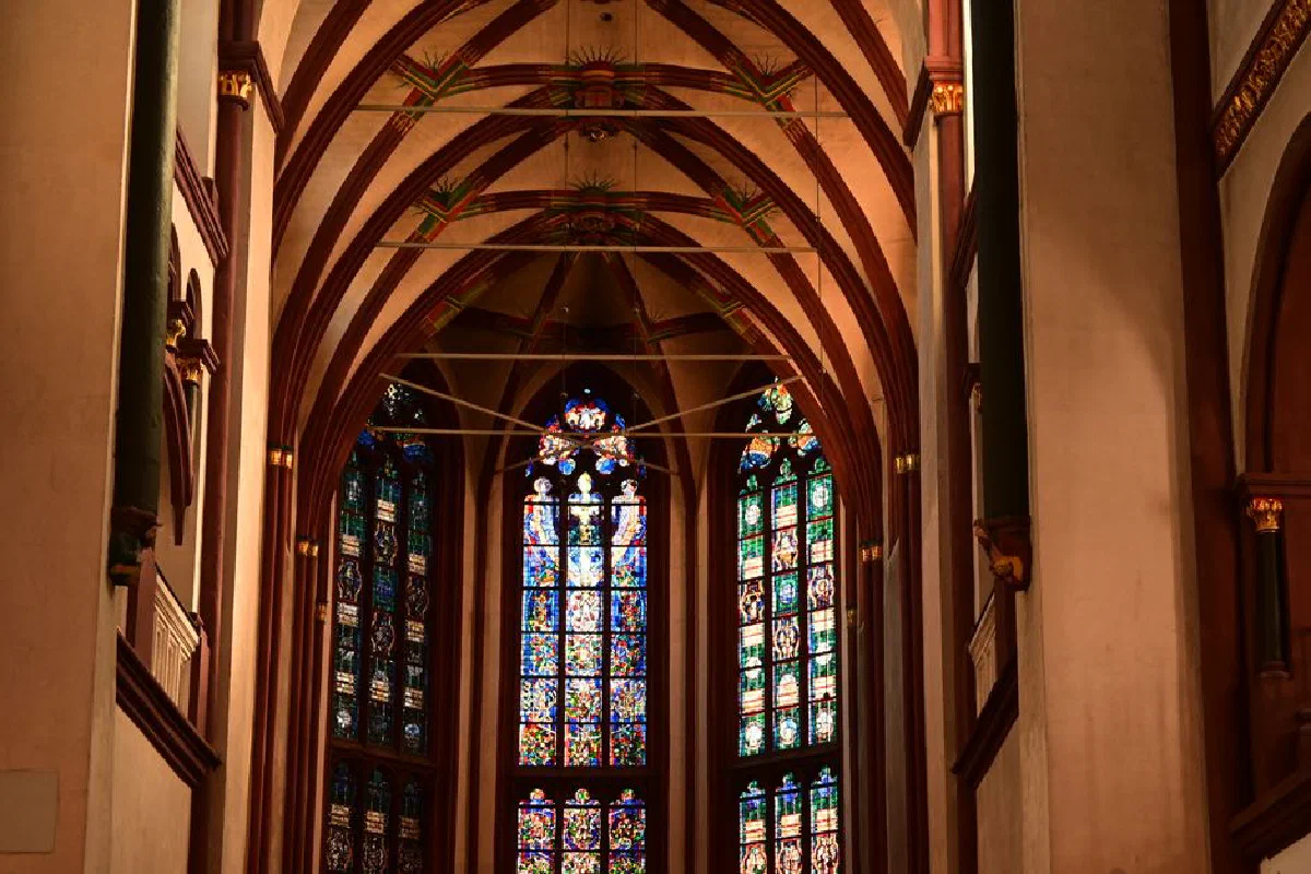 Intricate stained glass windows inside a majestic Gothic cathedral, showcasing religious art.