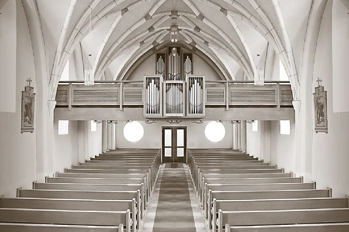 Symmetrical church interior highlighting architectural details and organ pipes.