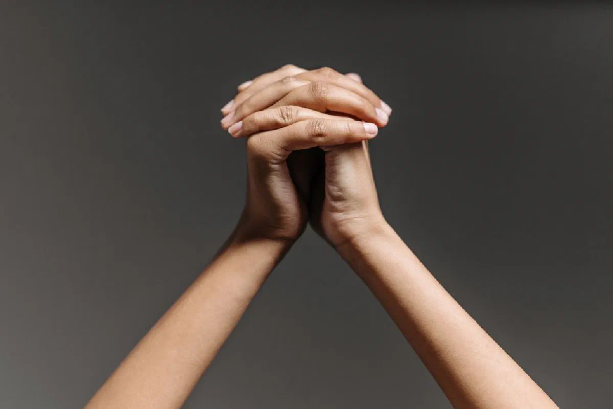 A detailed close-up of two hands clasped together against a neutral backdrop, symbolizing unity.