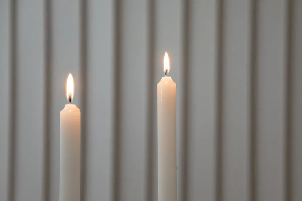 Close-up of two lit candles with a serene, minimalistic backdrop.