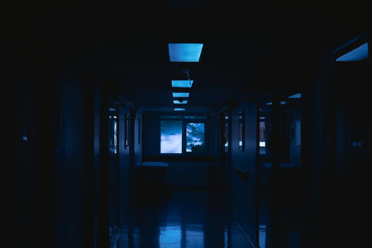A mysterious dark corridor with eerie glowing lights and an illuminated window view.