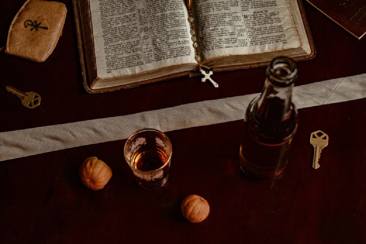 A symbolic arrangement featuring a Bible, rosary, and keys on a dark wooden table.