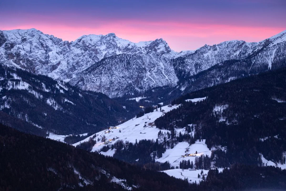 Breathtaking view of snowy mountains and valleys at sunset in the Italian Alps.