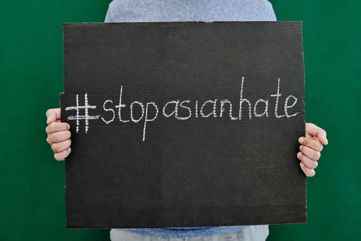 Close-up of hands holding a placard with #StopAsianHate message advocating against Asian hate.
