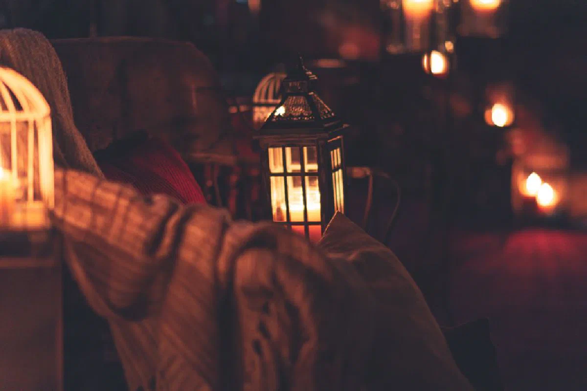 Warm candlelit scene featuring lanterns and soft textiles creating a cozy atmosphere indoors.