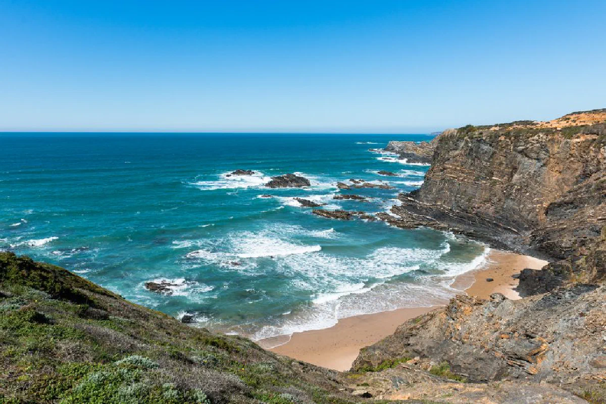 Breathtaking view of Portugal's rugged Alentejo coastline with dramatic cliffs and vibrant blue ocean.