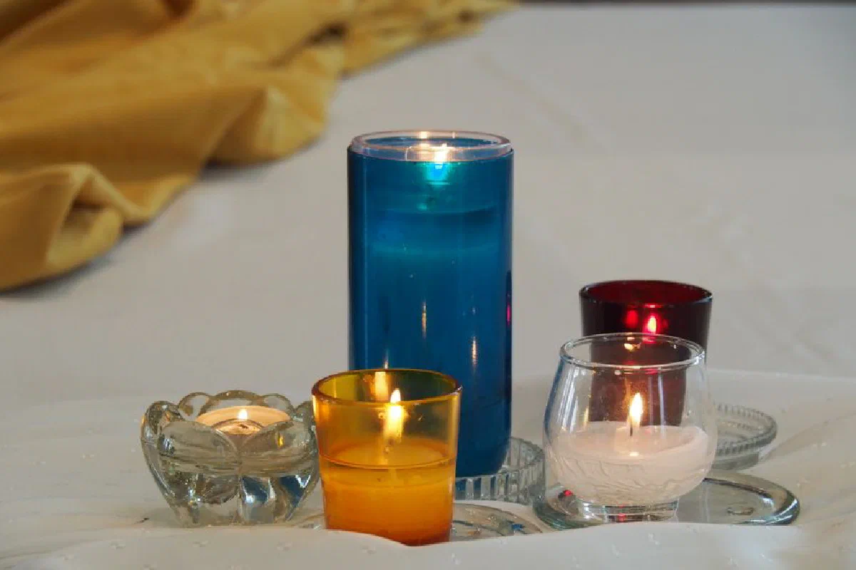 Five colorful candles lit on white linen, creating a warm and serene atmosphere.