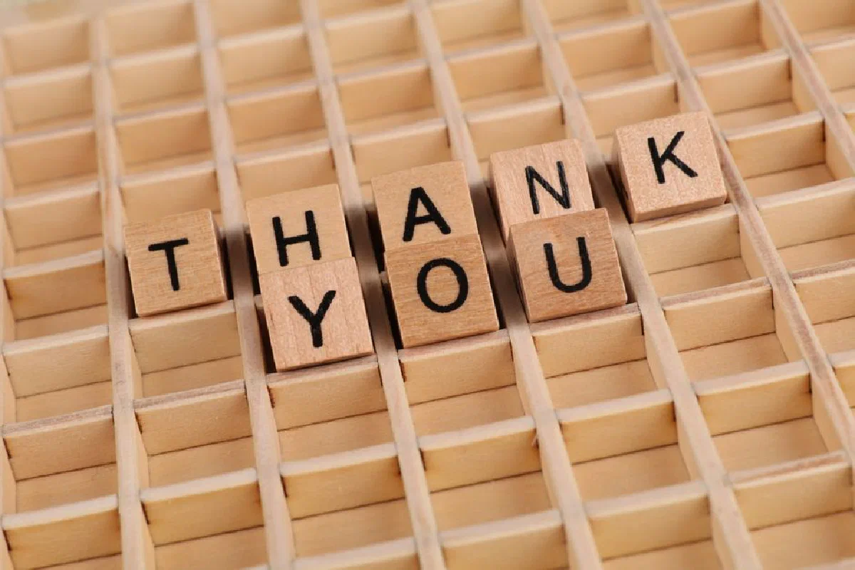 Creative arrangement of wooden blocks spelling 'Thank You' on a wooden surface.