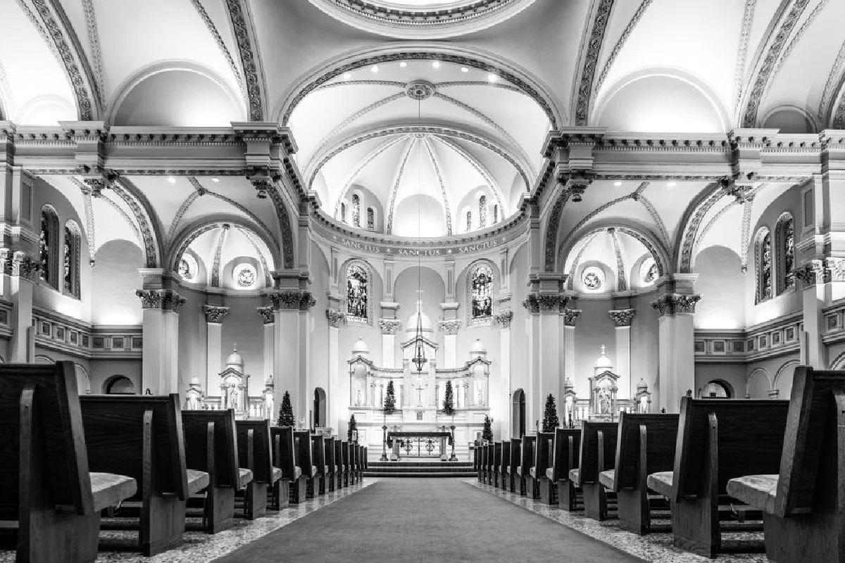 Elegant black and white depiction of a church's intricate architecture with empty pews.
