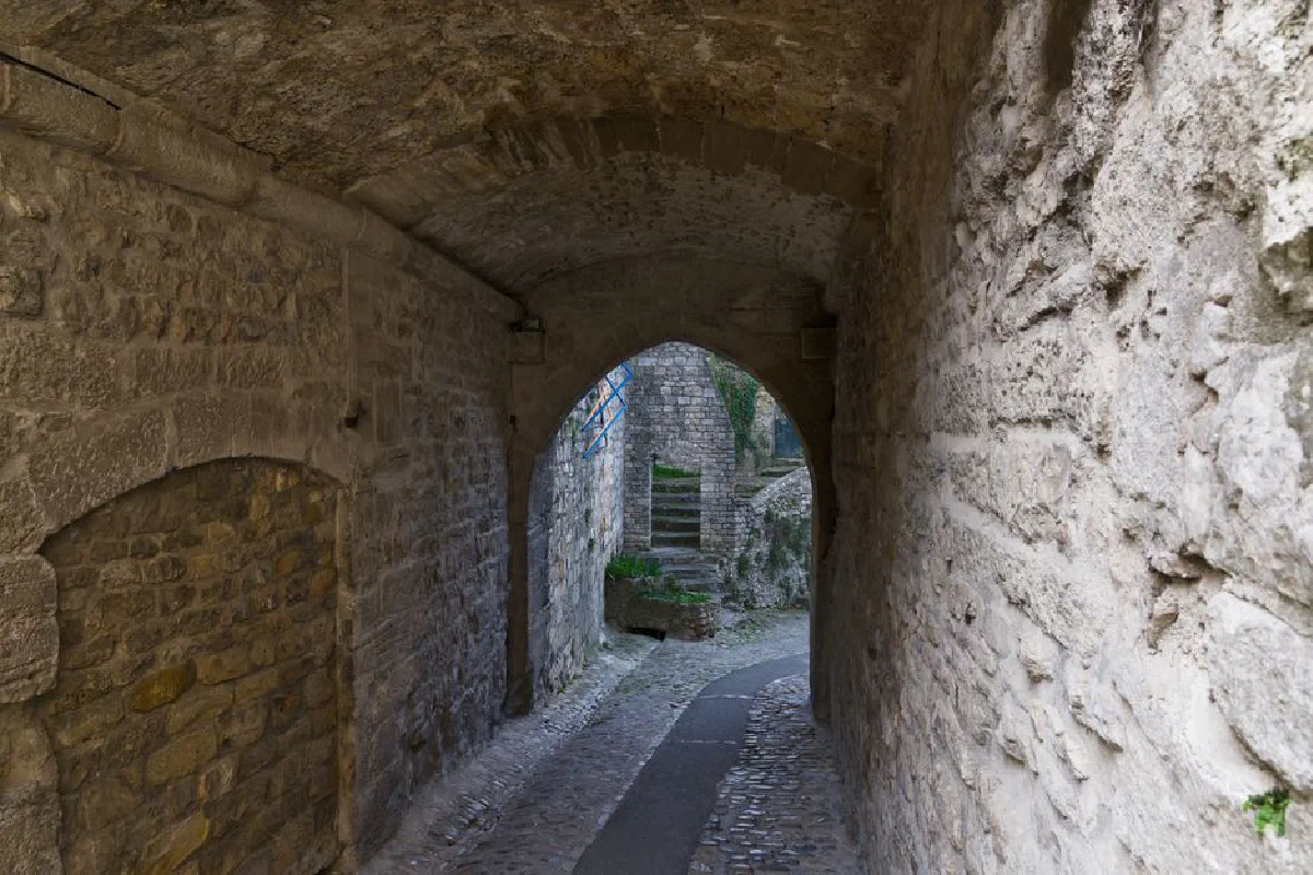 Ancient stone archway and pathway in Vaison-la-Romaine, France, showcasing medieval architecture.
