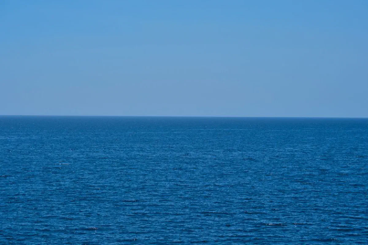 A tranquil seascape with endless blue ocean meeting the clear sky, capturing nature's calmness.