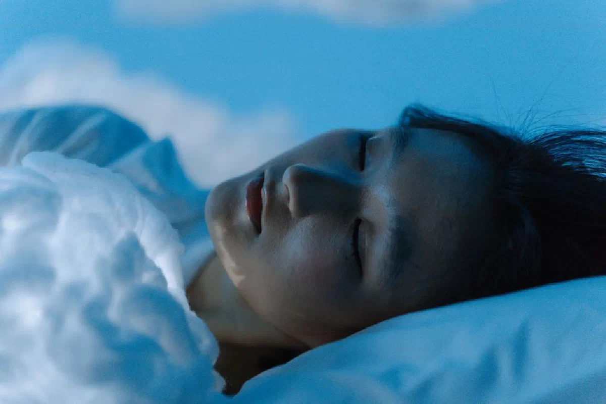 A tranquil scene of a woman sleeping comfortably on a white pillow, evoking peace.