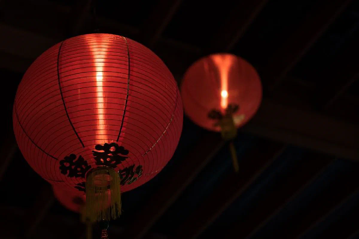 Traditional red Chinese lanterns hanging indoors, glowing warmly.