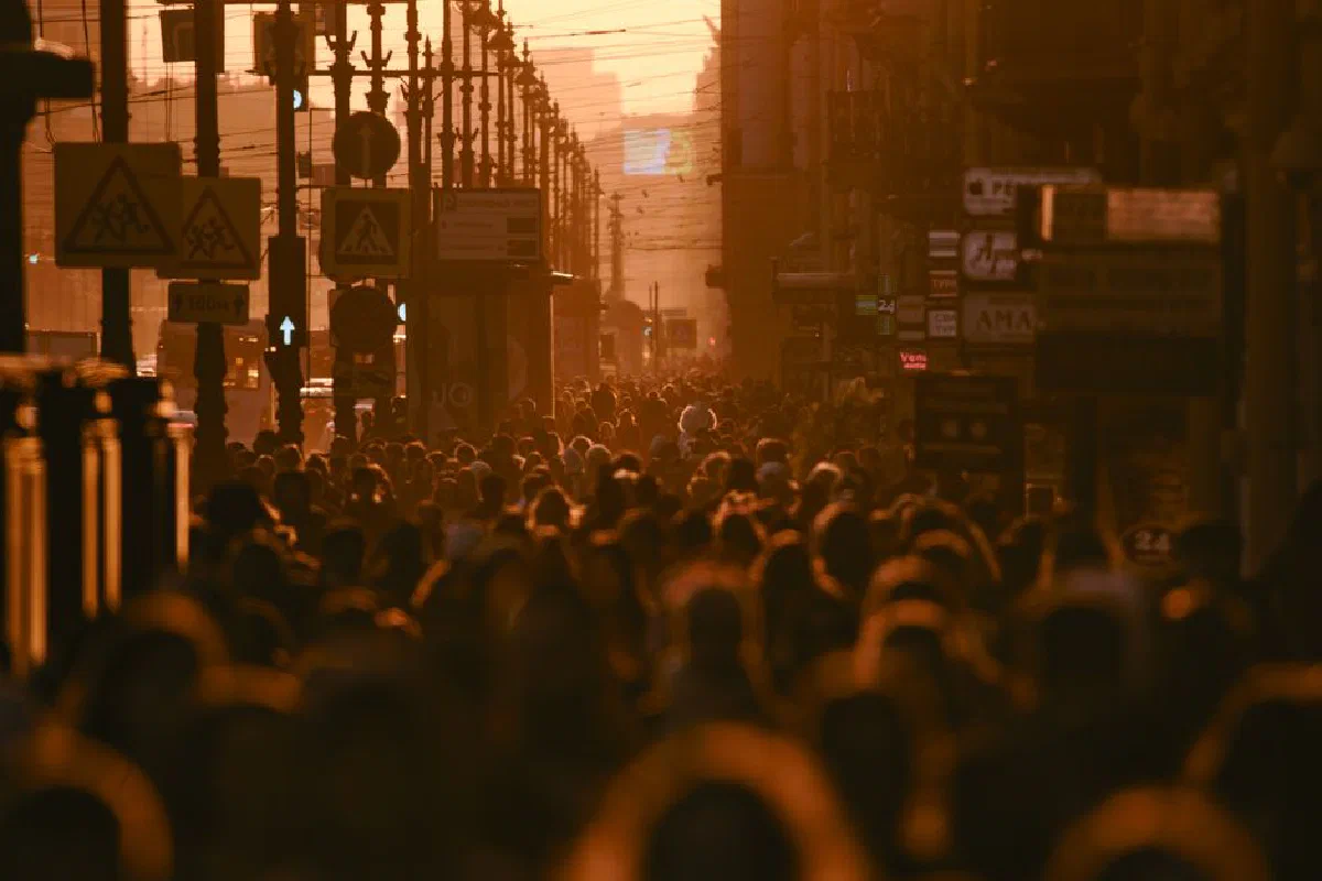 Bustling city street filled with pedestrians during a vivid sunset, capturing urban life energy.