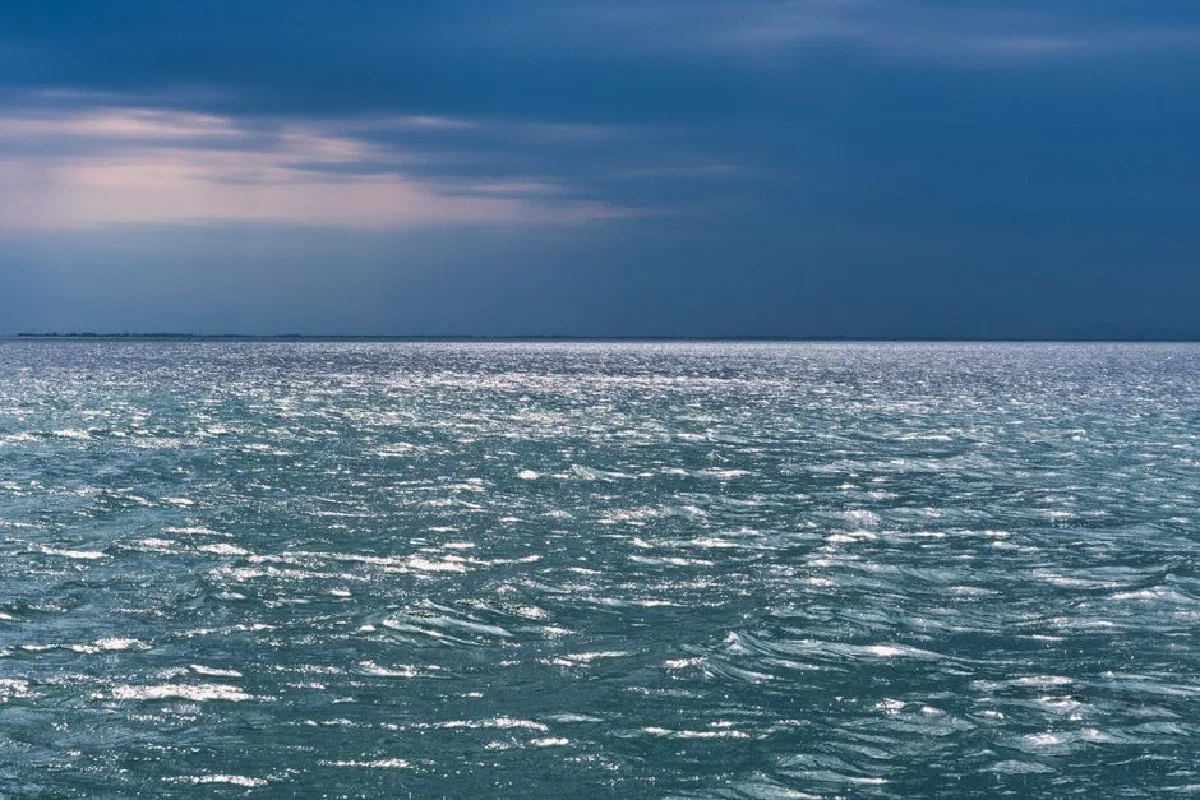A captivating seascape with rippling waves under moody clouds on a bright day.