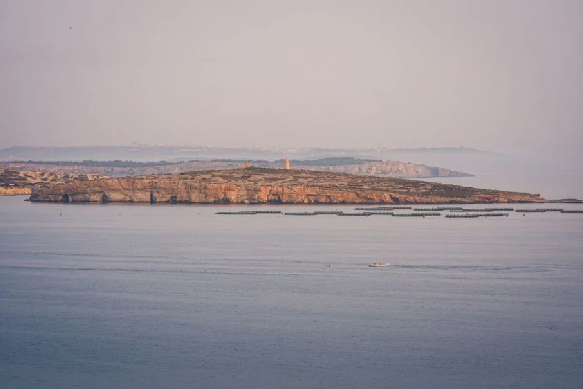 Tranquil seaside view of a cliff with a lighthouse and calm waters.