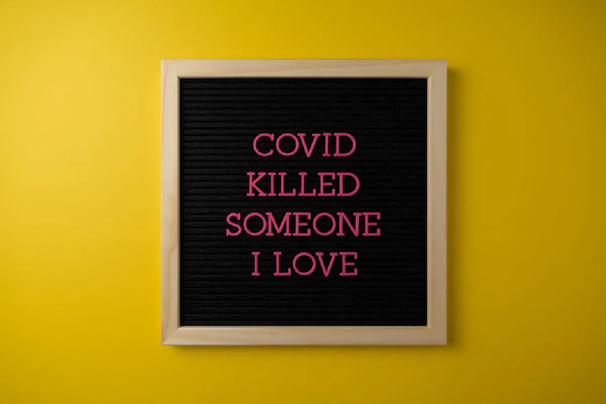 A heartfelt message about COVID loss displayed on a letter board against a yellow background.