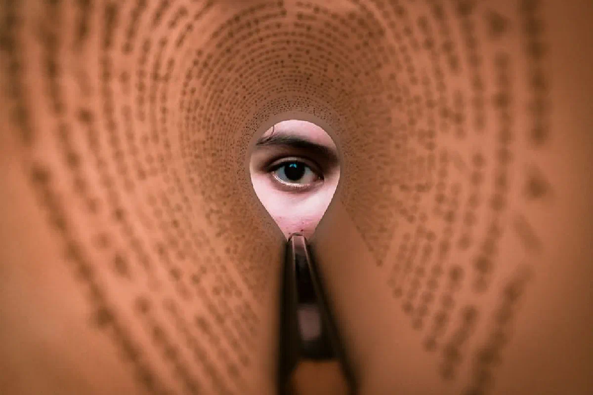 A person's eye looking through a rolled book page, creating a unique viewpoint.