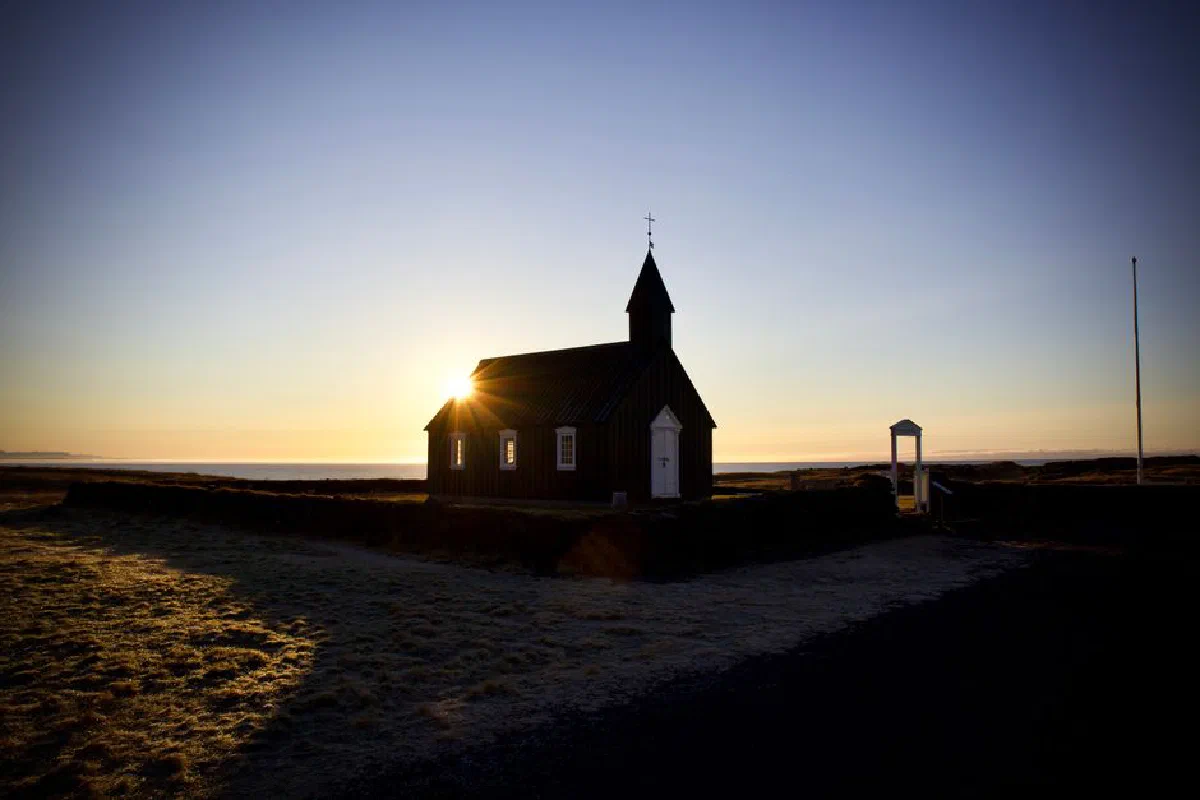 A stunning silhouette of Búðakirkja church at sunrise, capturing Iceland's serene coastal beauty.