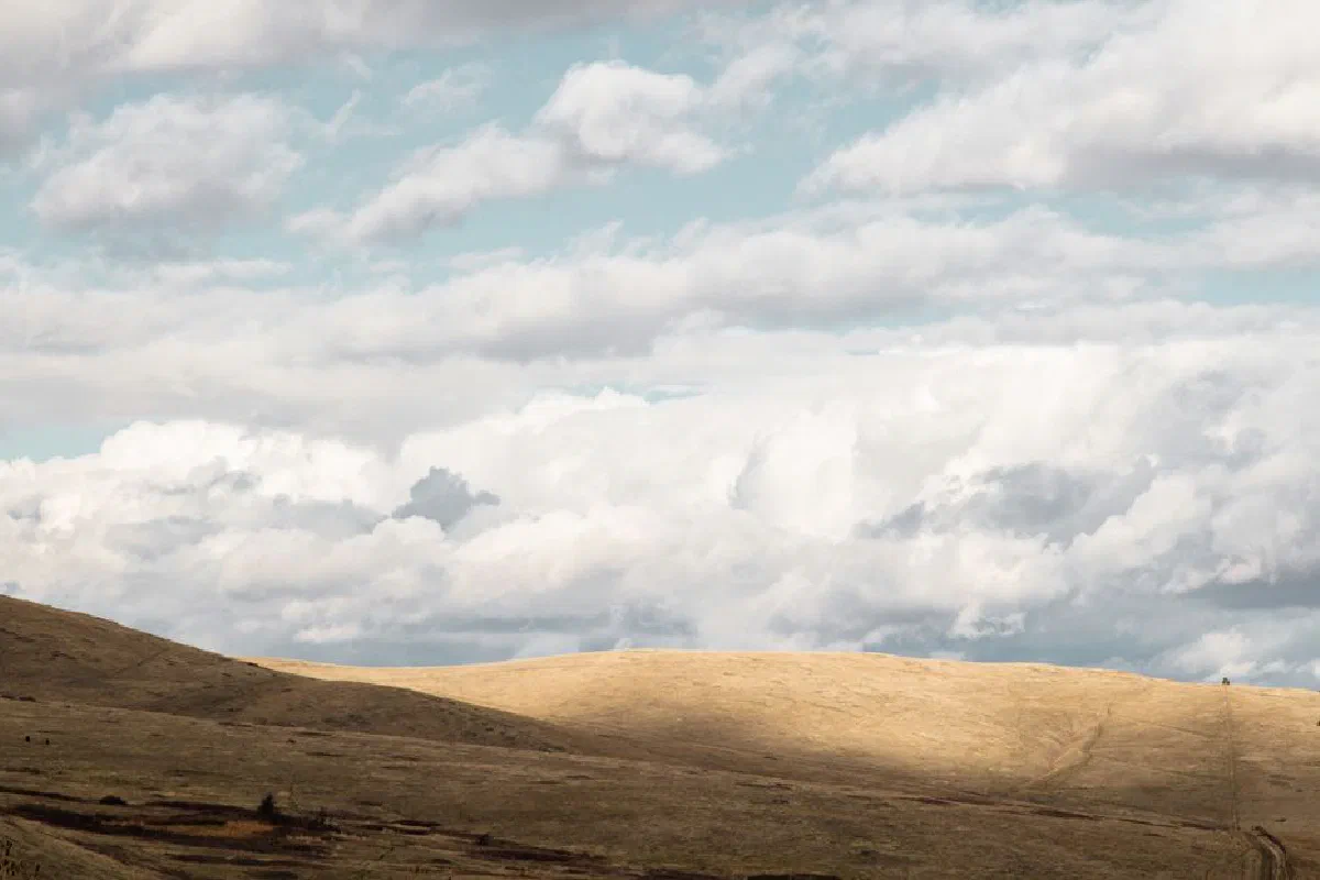 Expansive view of rolling hills and clouds in Montana's landscape, perfect for serene nature scenes.