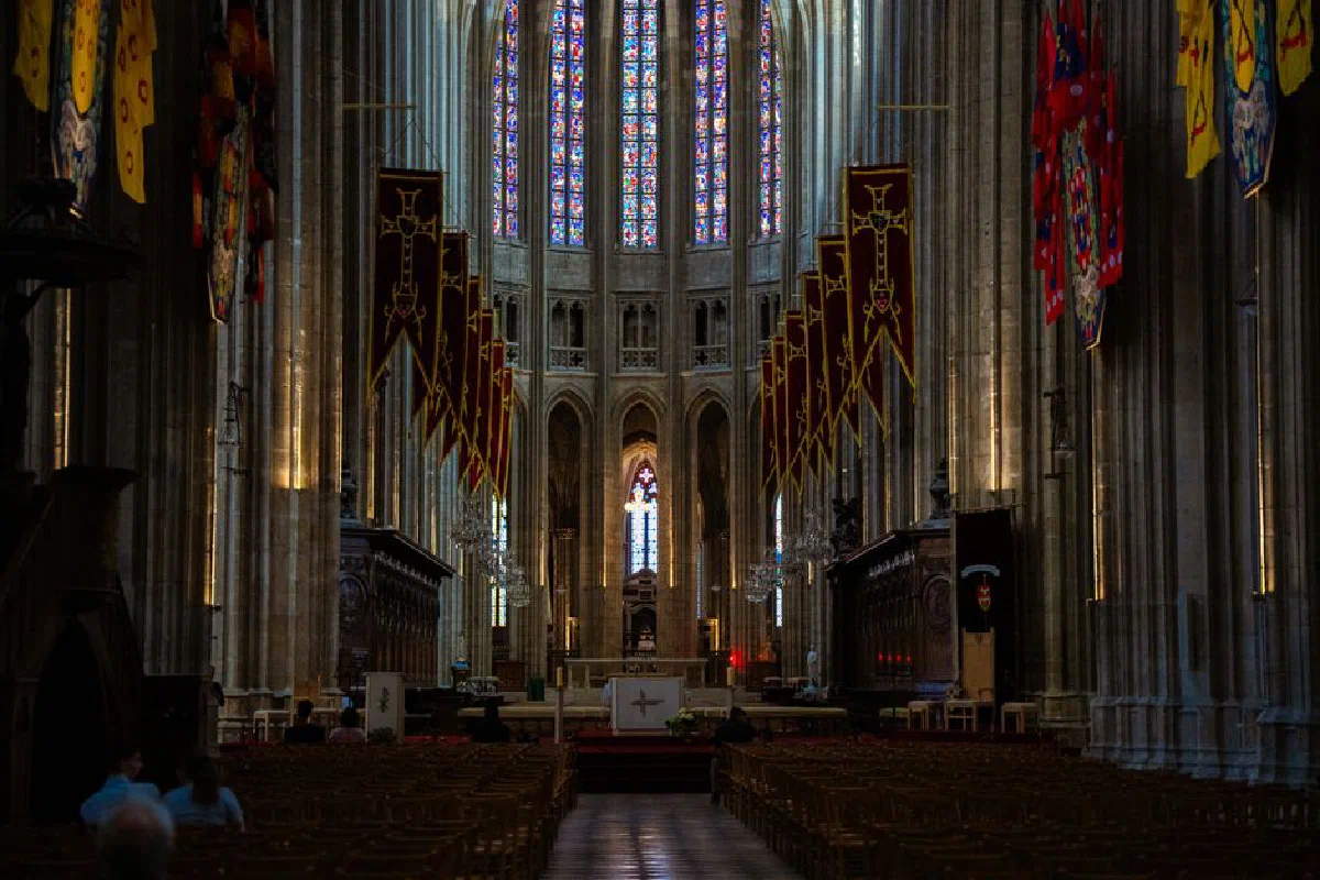 Majestic view of a Gothic cathedral interior featuring ornate stained glass and historic architecture.
