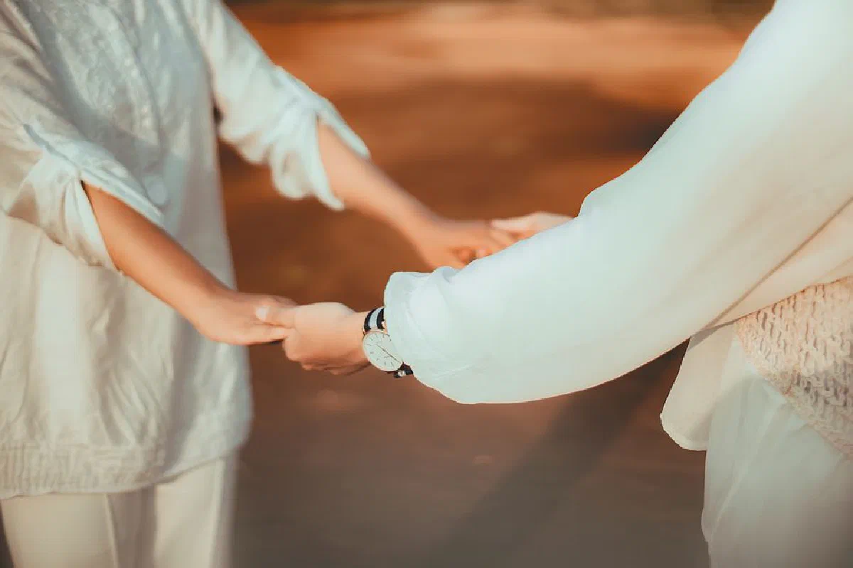 Two people holding hands outdoors, showcasing connection and friendship.