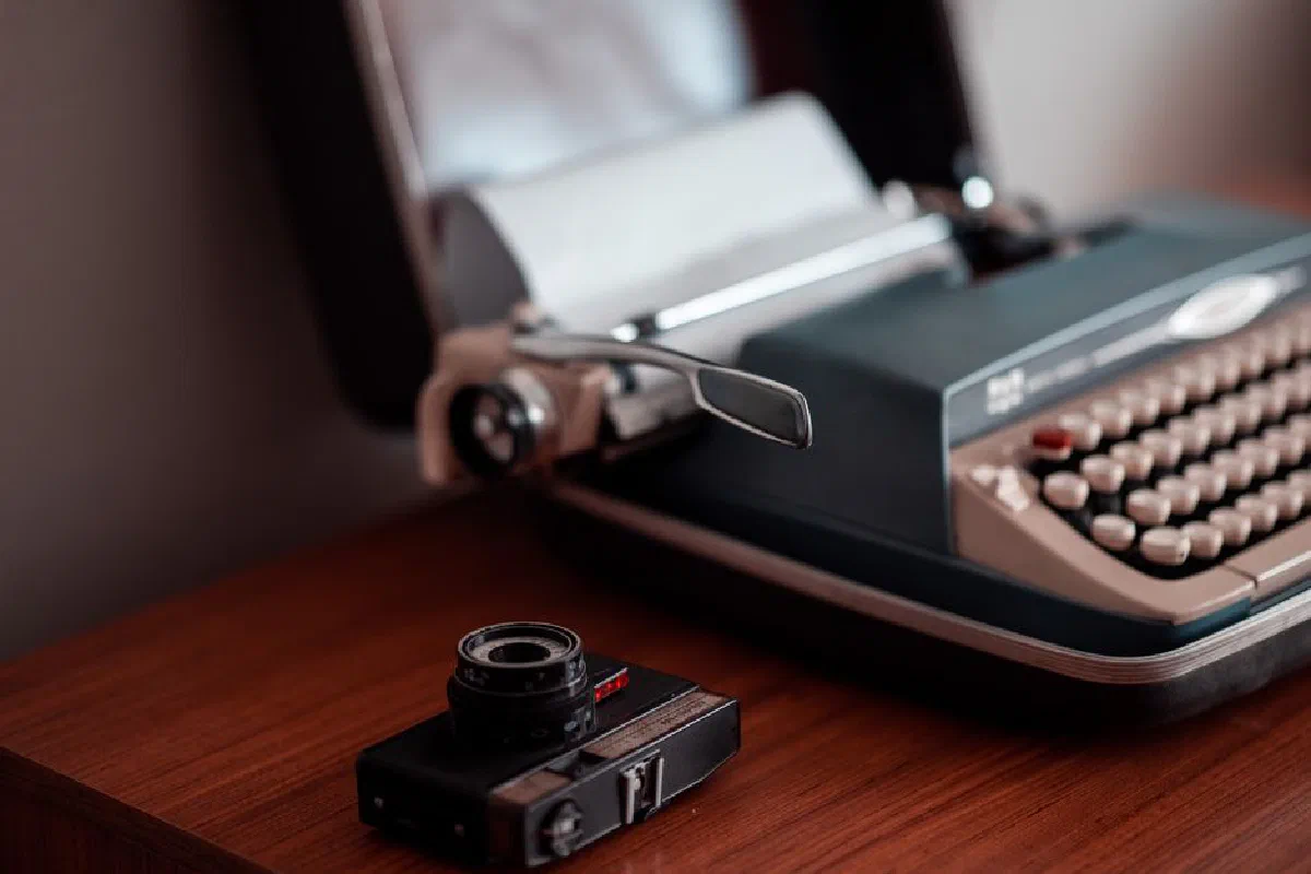 A nostalgic scene with a typewriter and vintage camera atop a wooden desk.