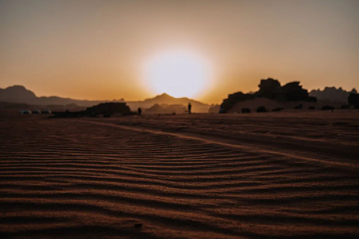 Dramatic sunset casting warm glow over the vast barren Wadi Rum desert landscape.