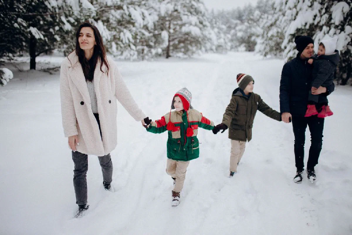 A happy family walking together in a snowy winter forest, enjoying the outdoors.