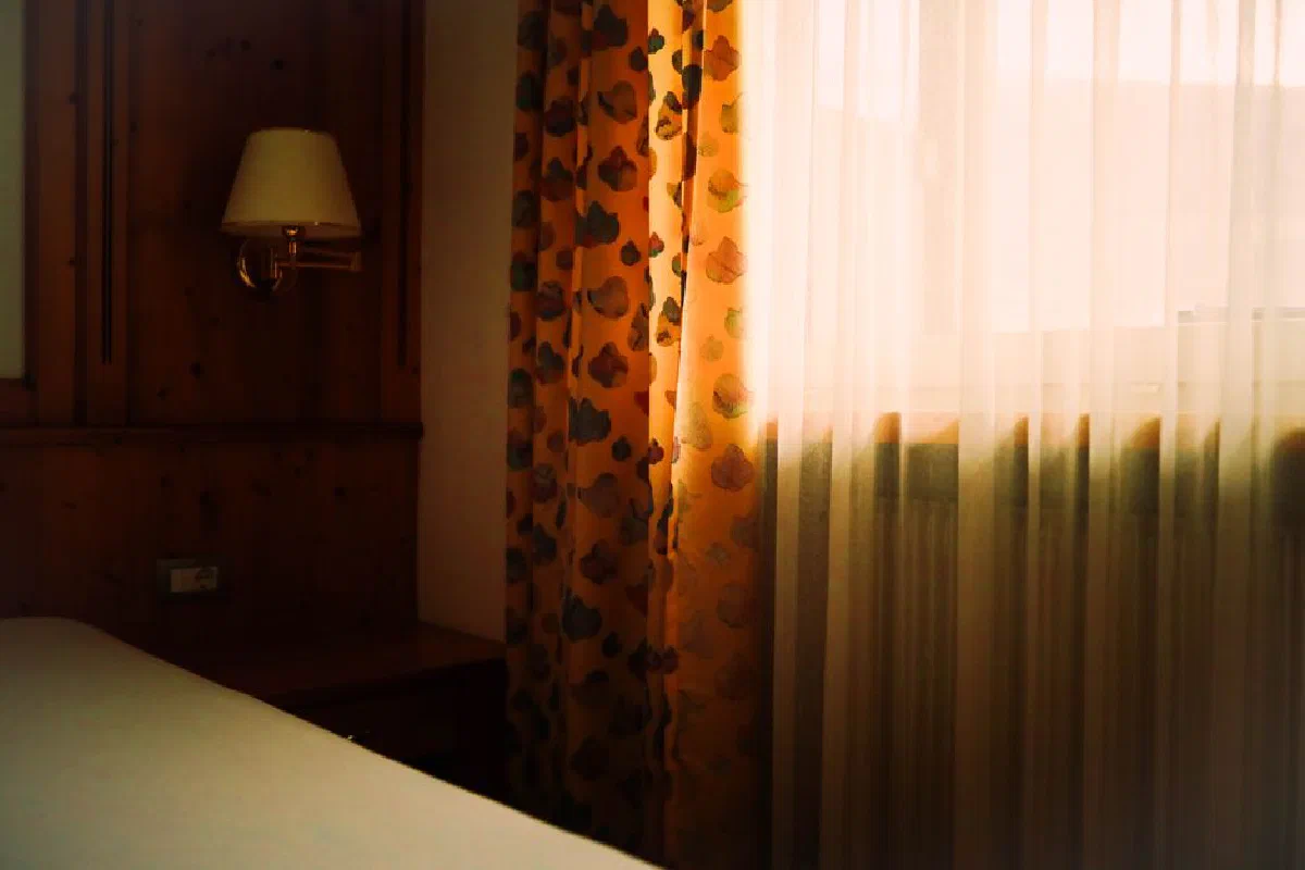 A cozy bedroom with sunlight filtering through curtains, creating a warm atmosphere.