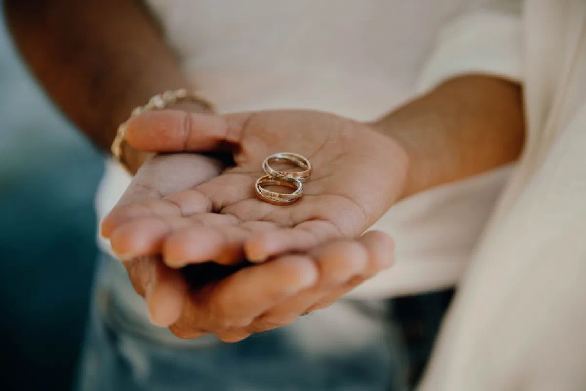 Two hands gently holding a pair of wedding rings symbolizing love and commitment.