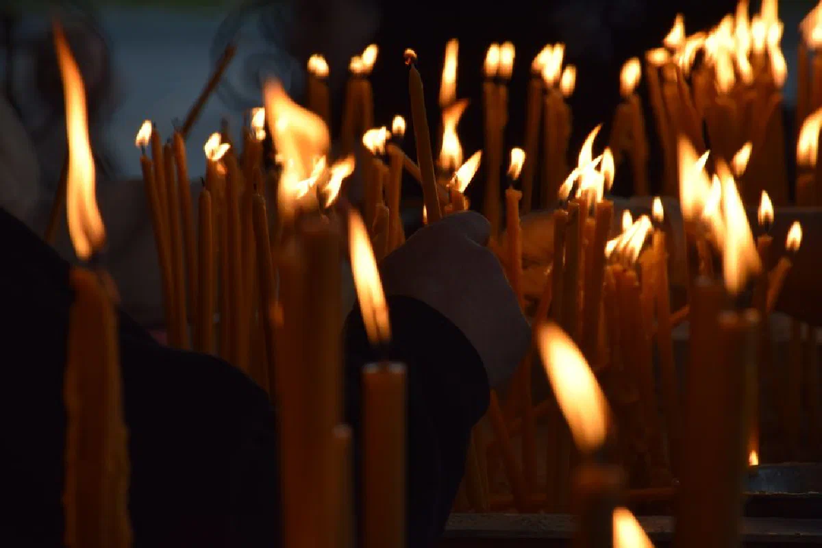 A close-up of numerous lit candles at a ceremonial event, creating a warm glow.