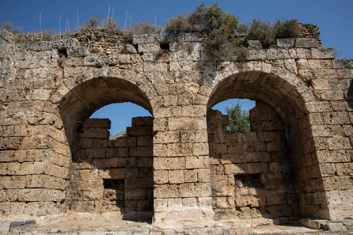 Explore the rugged beauty of ancient stone arches in historic ruins under a clear blue sky.