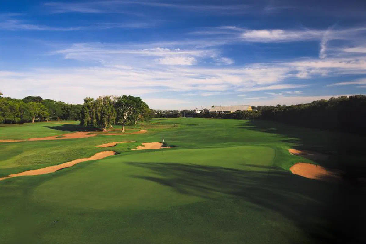 Aerial view of a lush green golf course under a blue sky, perfect for outdoor sports enthusiasts.
