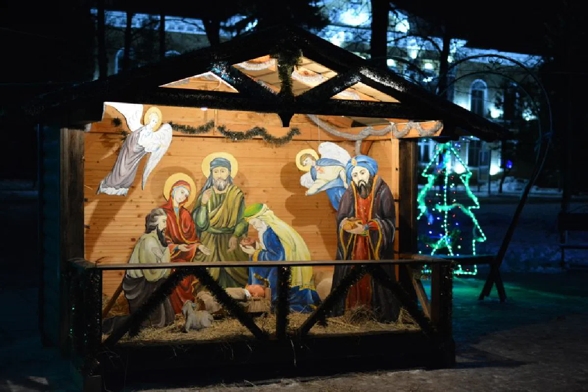 Illuminated nativity scene depicting Jesus' birth with vibrant Christmas lights.