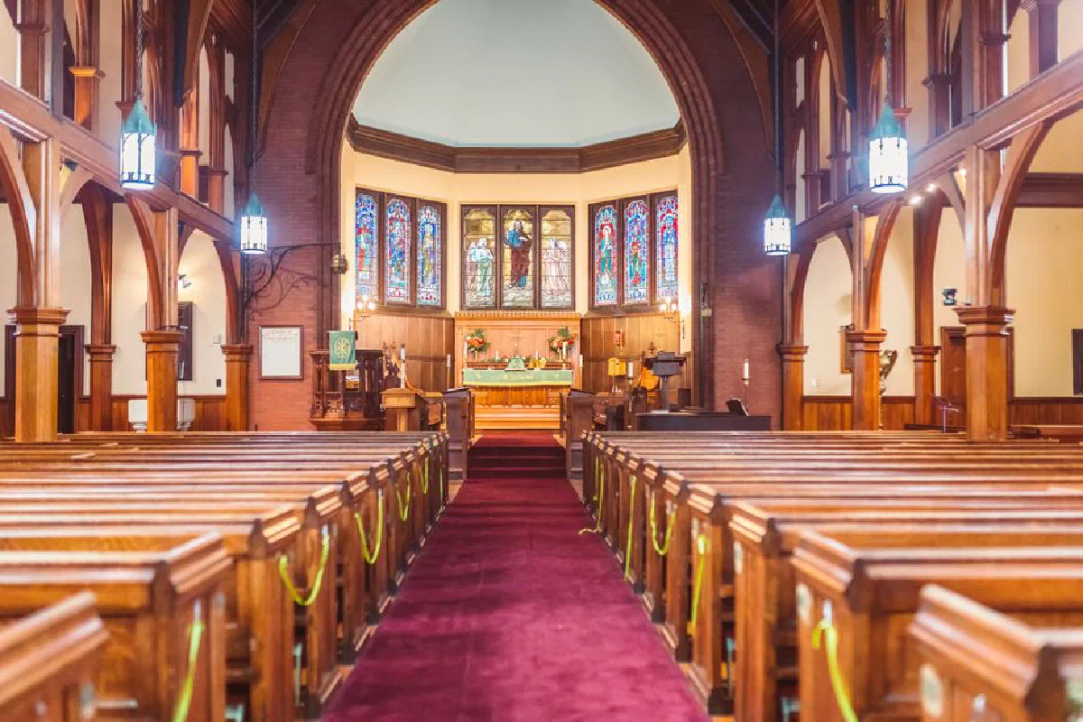 Elegant view of a historic church interior with ornate altar and stained glass windows.