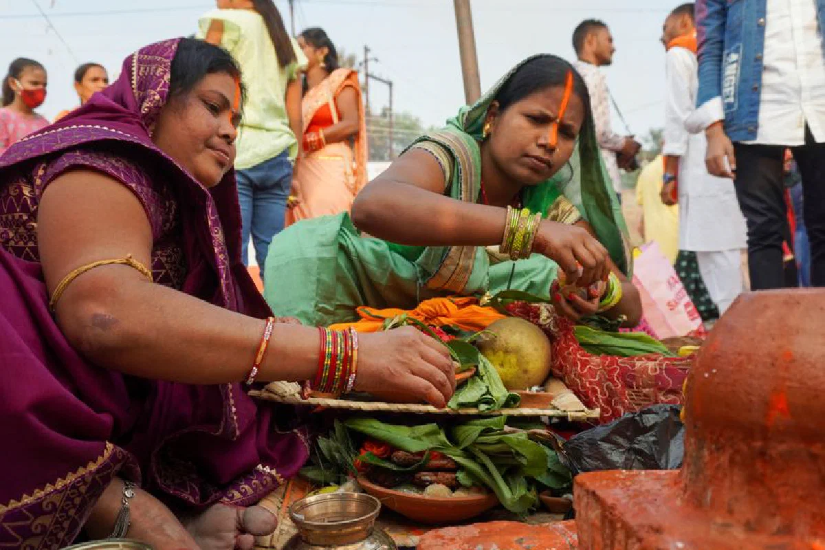 Women in traditional clothing preparing offerings at an Indian festival.