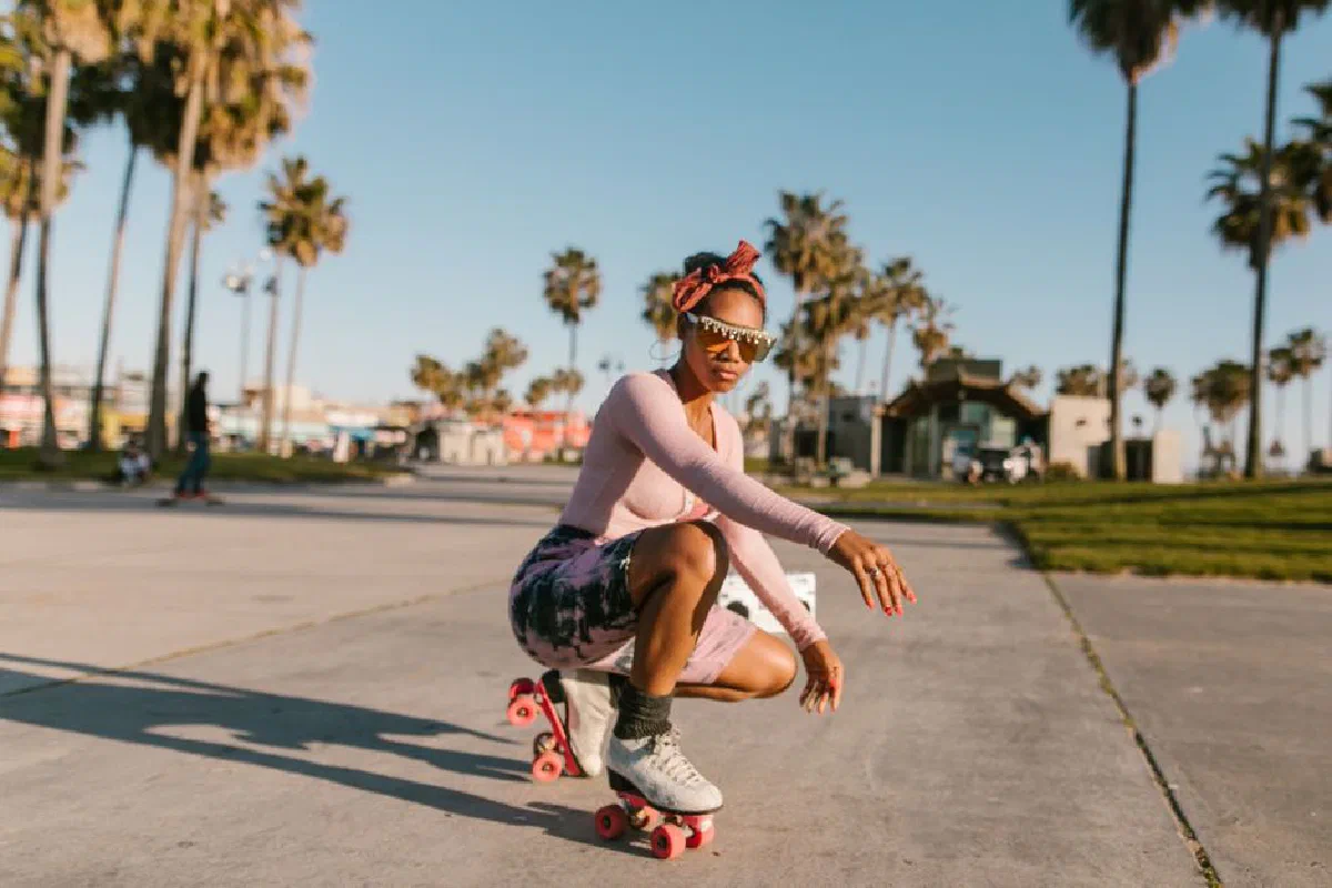 A fashionable black woman enjoying a sunny day roller skating in a park with palm trees.