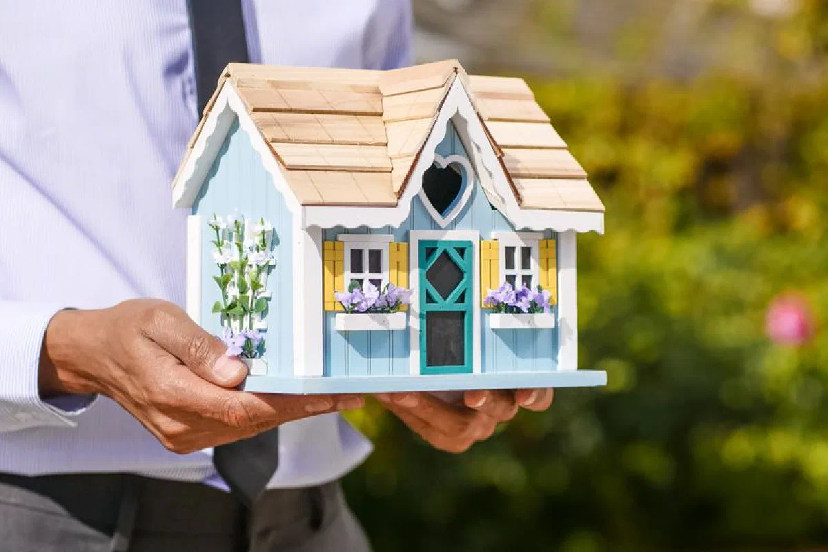 Close-up of a person holding a decorative miniature house outdoors.