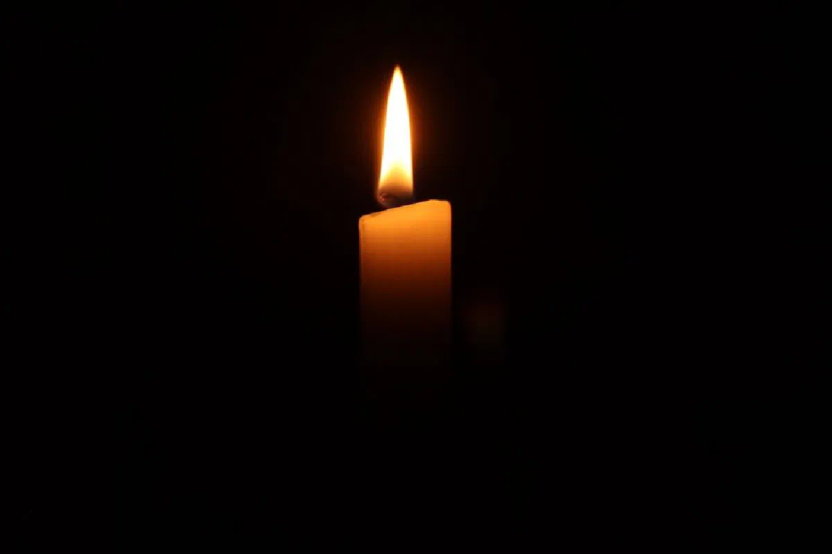 A single burning candle in the dark, casting a warm and serene glow.