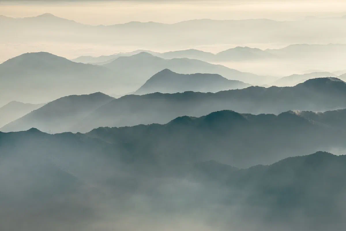 A peaceful mountain range enveloped in mist, creating a tranquil and serene landscape view.