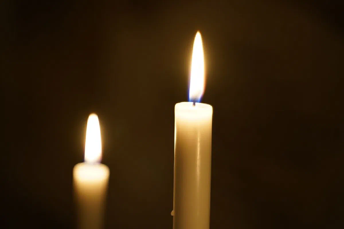 A tranquil close-up of two lit candles casting a warm glow against a dark background.