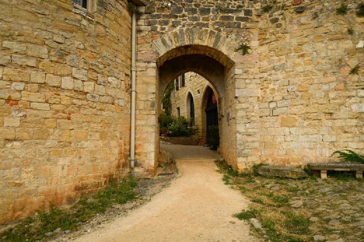 Charming stone archway leading into the historic village of Puycelsi, Occitanie, France.