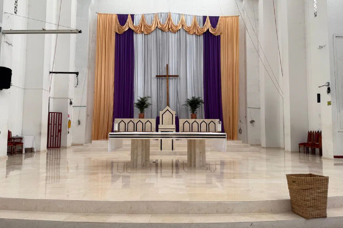 Spacious church interior featuring a central cross altar adorned with purple and gold drapes.
