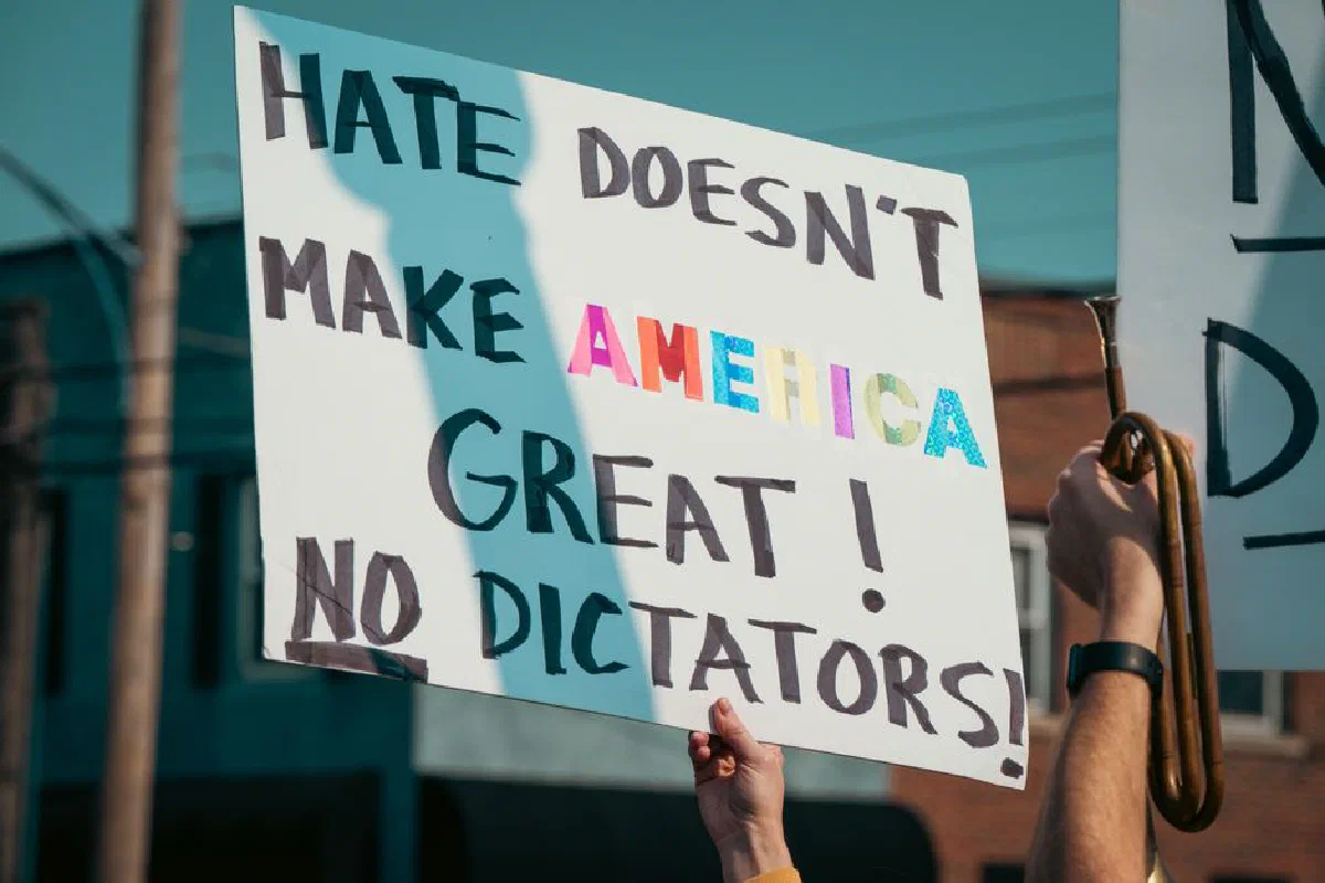 A protest sign with the message 'Hate Doesn't Make America Great!' during a daytime demonstration.