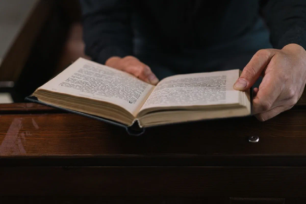 Close-up of hands holding an open book in a religious setting, perfect for themes of spirituality and contemplation.